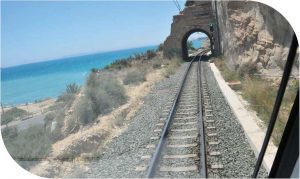 Foto portada capítulo 11. Vías del tren a punto de pasar por un túnel desde la perspectiva del conductor. Al fondo se ve una playa.